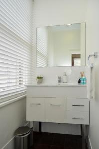 a white bathroom with a sink and a mirror at Albany Central Apartments in Albany