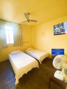 a hotel room with two beds and a fan at Hotel Nacional Montes Claros in Montes Claros