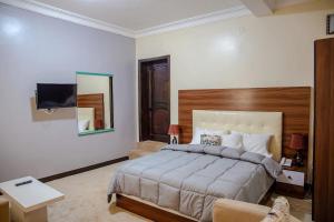 a bedroom with a large bed and a mirror at EZRA BOUTIQUE Hotel By The Weekender Ltd in Kigali