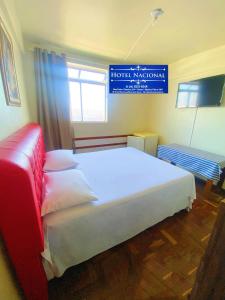 a bedroom with a large bed and a sign on the wall at Hotel Nacional Montes Claros in Montes Claros