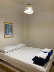 um quarto com uma cama com lençóis brancos e um candeeiro em Apartamentos Primavera em Jardín