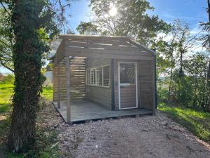 La Cabane Du Champ Du Possible في Uxeau: كوخ خشبي مع شرفة بجانب شجرة