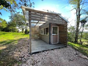 a small wooden cabin with a deck in a field at La Cabane Du Champ Du Possible in Uxeau