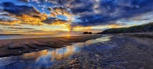 a sunset on a beach with a reflection in the water at The Gaslight Inn Holiday Apartments & Licenced Restaurant Rossnowlagh in Rossnowlagh