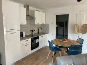 a kitchen with white cabinets and a table and chairs at Le cottage de Christine in Vresse-sur-Semois