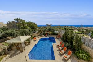 an outdoor swimming pool with chairs and umbrellas at The Almonds Luxury Villa in San Lawrenz