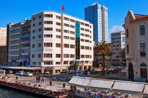 a large white building next to a river with buildings at Kilim Hotel Izmir in İzmir