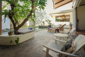 un patio con un albero, sedie e una piscina di Bias Villa Seminyak a Seminyak