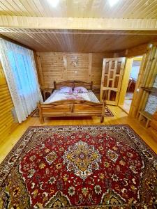 a room with a bed with a large red rug at Садиба "Три Царі" in Yaremche