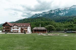 a large building in a field with mountains in the background at Popasul Craiului in Zărneşti