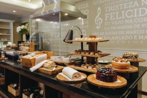 um balcão de padaria com diferentes tipos de bolos e pastelarias em Bourbon Curitiba Hotel & Suítes em Curitiba