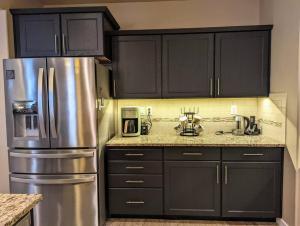 a kitchen with black cabinets and a stainless steel refrigerator at Spacious 3-bedroom home with outdoor space in Eugene