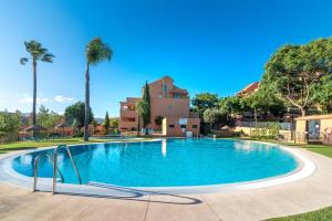 une piscine avec des palmiers et un bâtiment dans l'établissement Marbella Penthouse apartment, à Marbella
