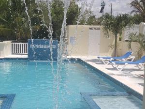 una fuente en una piscina con 2 sillas azules en Westmore Beach Villas Limited, en Whitehouse