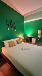- une chambre avec un grand lit blanc aux murs verts dans l'établissement Peixe Gordo Hotel, à Icapuí
