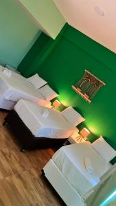Cette chambre verte comprend 3 lits et un mur vert. dans l'établissement Peixe Gordo Hotel, à Icapuí