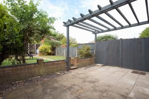 eine Pergola im Hinterhof mit einem Zaun in der Unterkunft Stylish & Spacious 3BR Home With Private Driveway in Bletchley