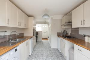 eine Küche mit weißen Schränken und einem Waschbecken in der Unterkunft Stylish & Spacious 3BR Home With Private Driveway in Bletchley