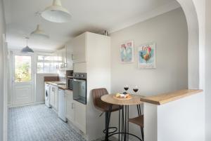 una cocina con armarios blancos y una mesa pequeña. en Stylish & Spacious 3BR Home With Private Driveway, en Bletchley