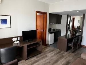 a living room with a desk and a kitchen at Hotel Bonaparte Flat Particular A in Brasilia
