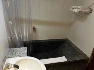 a bathroom with a white sink and a shower at Hotel Bonaparte Flat Particular A in Brasilia