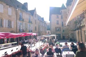 a group of people sitting at tables in a street at Cité médiévale, charme & calme, bien placé in Sarlat-la-Canéda