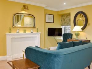 a living room with a blue couch and a fireplace at 2 The Reading Room Cottages - Uk31801 in Barningham