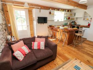 sala de estar con sofá marrón y cocina en Beekeeper's Cottage, en Lamphey