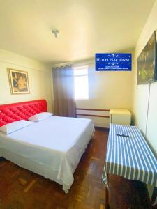 a bedroom with a large bed and a red bench at Hotel Nacional Montes Claros in Montes Claros