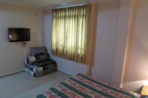 a bedroom with a bed and a chair and a television at New Orchid Hotel in Singapore