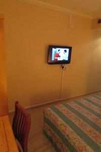 a room with a tv on a wall with a bed at New Orchid Hotel in Singapore +13 photos