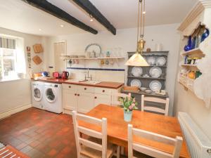 a kitchen with a table and a washing machine at Clematis Cottage in Bakewell