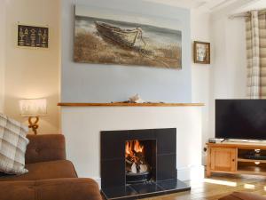 a living room with a fireplace and a tv at Compass Point in Brixham