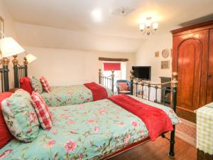 a bedroom with two beds and a tv at Clematis Cottage in Bakewell