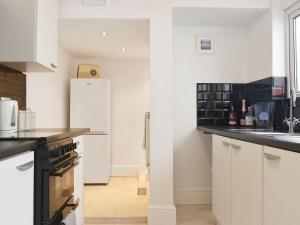 a kitchen with white cabinets and a refrigerator at Compass Point in Brixham