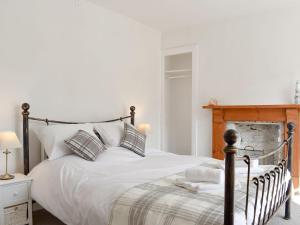 a bedroom with a bed with white sheets and pillows at Compass Point in Brixham