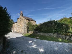 un antico edificio in pietra con un muro di pietra di Clematis Cottage a Bakewell