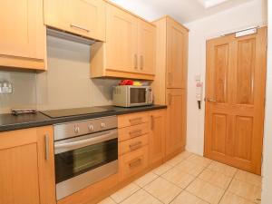 a kitchen with wooden cabinets and a microwave at Y Castell Apartment 3 in Porthmadog