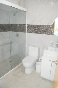 a white bathroom with a toilet and a shower at Frente al mar, increíble vista, nuevo estudio 1 C in Cancún