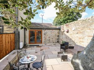 un patio con tavolo e sedie e un edificio di April Cottage a Keighley