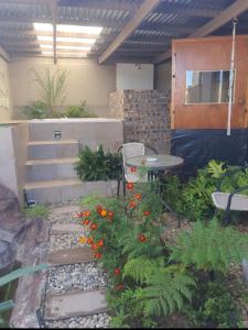 un jardín con mesa, sillas y flores en Revive Guesthouse en Darling