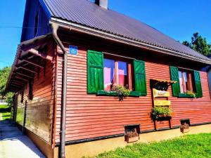 a wooden house with green windows and plants on it at Kuća za odmor-Kućica in Mrkopalj