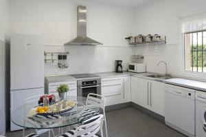 cocina con mesa de cristal y armarios blancos en CASONA QUINTA HERMINIA, en Gijón