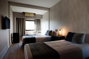 Habitación de hotel con 2 camas y TV en Believe Madero Hotel en Buenos Aires