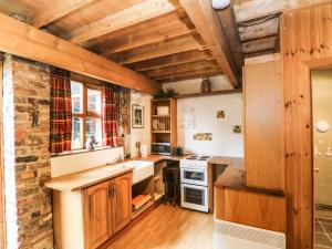 a kitchen with wooden cabinets and a brick wall at The Toolshed in Warrington