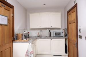 a kitchen with white cabinets and a microwave at Arthur Turner, The Apple Rooms in Stockbridge