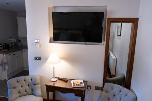 a living room with two chairs and a television on a wall at Arthur Turner, The Apple Rooms in Stockbridge