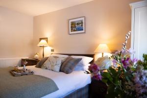 a bedroom with a bed and two lamps and flowers at Arthur Turner, The Apple Rooms in Stockbridge