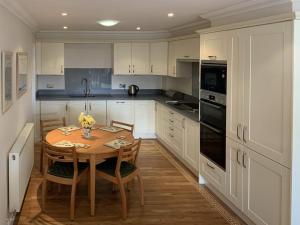 a kitchen with a wooden table and a kitchen with white cabinets at Woodside Cottage in Troutbeck Bridge