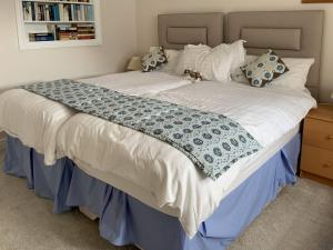 a large bed with a blue and white blanket on it at Woodside Cottage in Troutbeck Bridge
